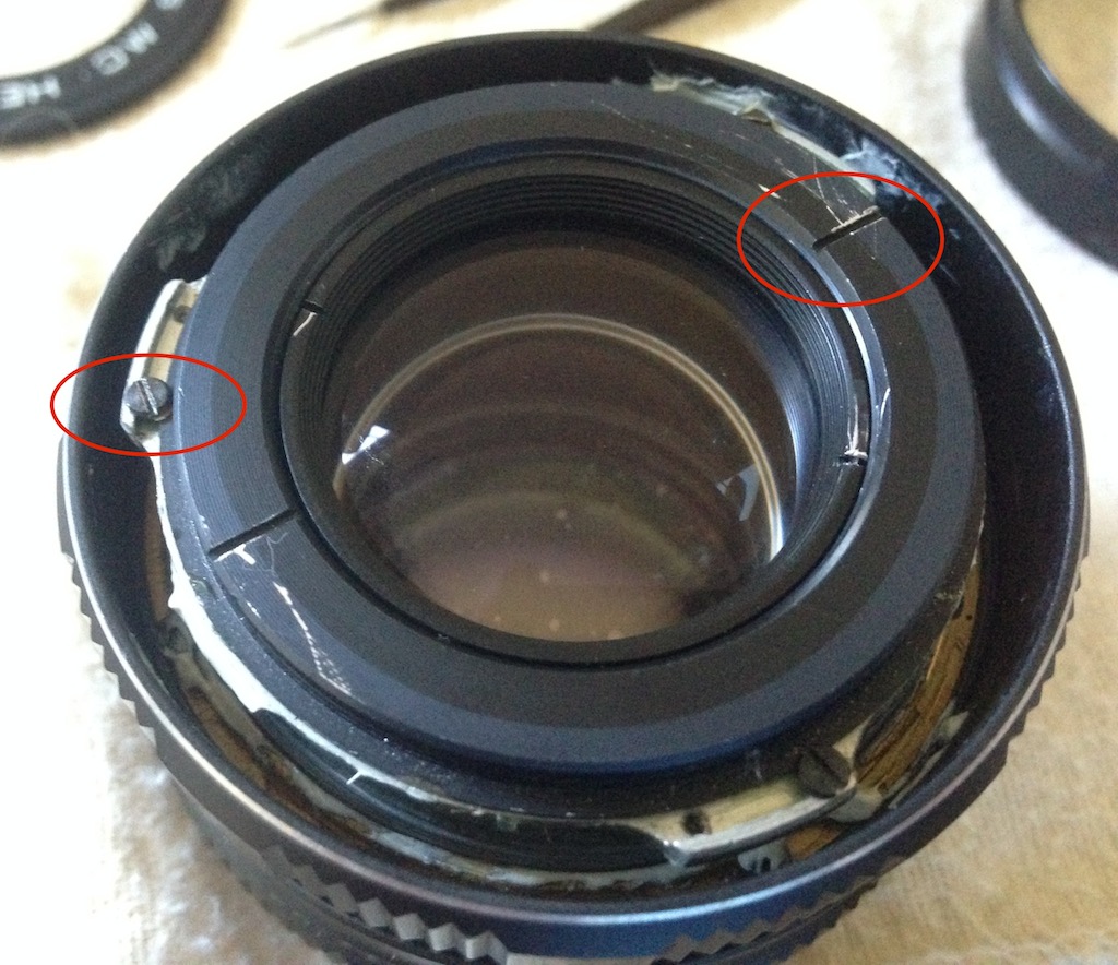 Figure 2: Lens front without front ring and filter holder. Circled red: glass holder ring dent, and one of the bolts that attach the core to the inner barrel.